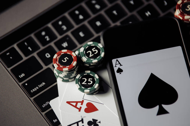 Online poker casino thema. Gokken chips, smartphone en speelkaarten op toetsenbord close-up - Foto, afbeelding