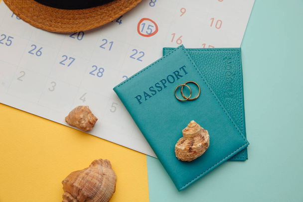 Kalender met paspoorten, hoed en ringen op kleurrijke tafel. Huwelijksreis, huwelijksconcept - Foto, afbeelding
