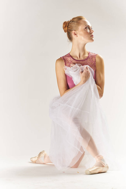 bailarina de mujer en zapatos puntiagudos y en un tutú sobre un fondo claro posa posando piernas modelo de baile - Foto, Imagen