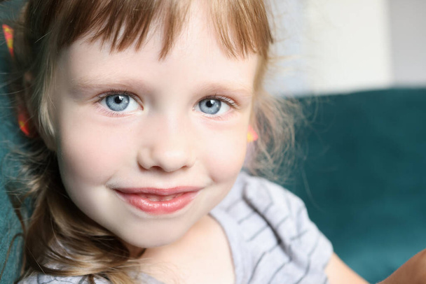Portrait de petite fille aux yeux bleus et au léger sourire - Photo, image