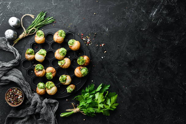French food. Baked snails with pesto sauce on a black stone background. Top view. Free space for your text. - Фото, зображення