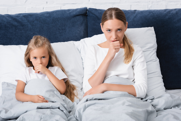 母親と子供が自宅でベッドで咳をする選択的な焦点  - 写真・画像