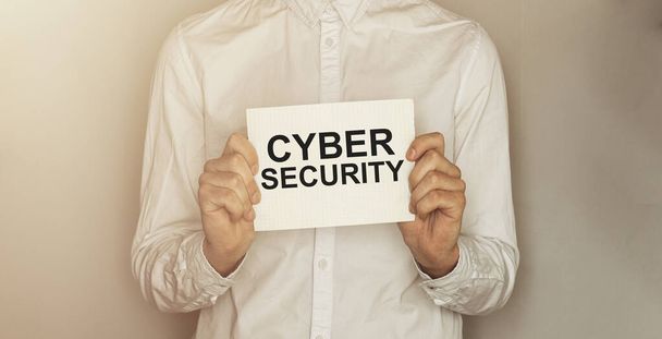 Mann nehmen Sie ein Papier mit Text Cyber Security auf dem Hemd mit Bürohintergrund - Foto, Bild