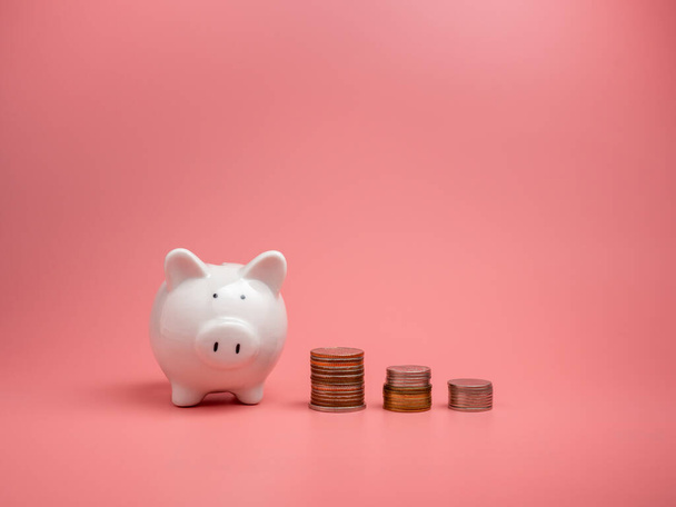 White piggy bank and coin On a pink background with copy space for design. - 写真・画像