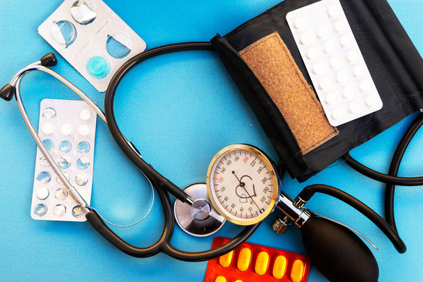монитор кровяного давления и красное сердце и таблетки на синем фоне - Фото, изображение