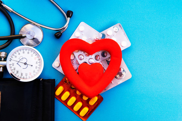 血圧計と赤い心臓と青い背景の丸薬 - 写真・画像