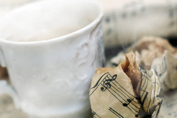 Biały kubek kawy z parą i muzyczną nutą tak blisko - Zdjęcie, obraz