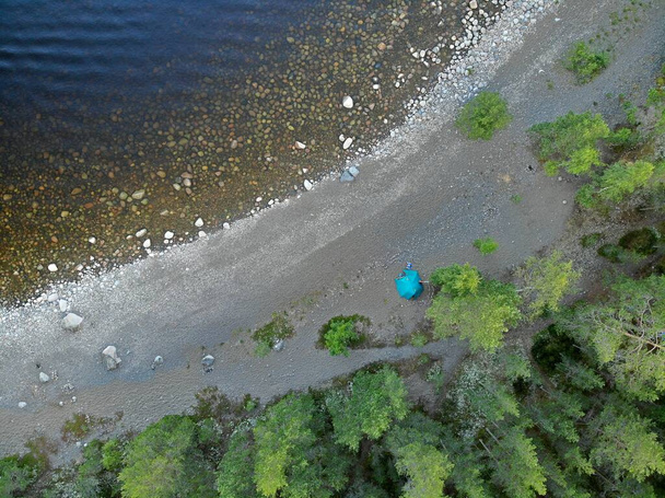 Playa rocosa costera con tienda de campaña y camping. Piedras en el fondo de agua clara - Foto, imagen