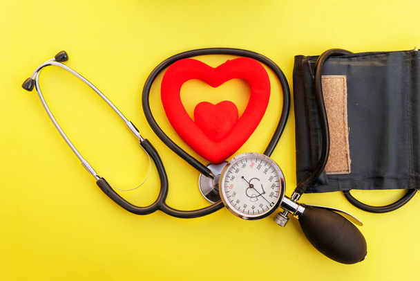 Тонометр з червоним серцем на жовтому фоні пристрій для вимірювання тиску листівки денної гіпертензії
 - Фото, зображення
