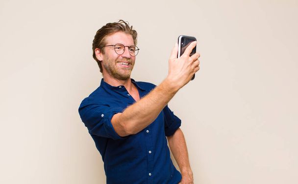 blonde adult man with a mobile smart telephone - Fotografie, Obrázek