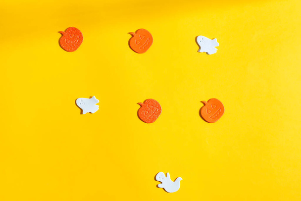 Holiday Helloween pano de fundo decorado abóboras cortadas à mão e fantasmas em um fundo amarelo, espaço de cópia. Vista superior. - Foto, Imagem