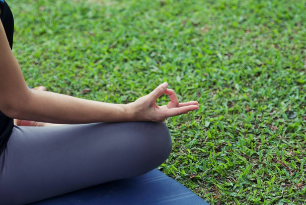 En la postura de loto de cerca, Yoga en el parque, al aire libre con efecto de luz, mujer sana. Concepto de estilo de vida saludable y relajación. - Foto, Imagen