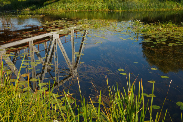 Reflexiones de las construcciones de un puente ferroviario sobre la superficie del agua del río - Foto, Imagen