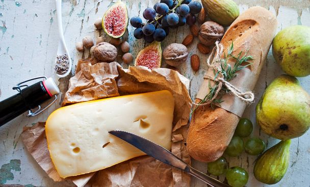 Frisches Brot mit Estragon auf altem Holzgrund, Draufsicht. Glutenfreies Mini-Baguette-Brot. Obst, Käse und Nüsse als Vorspeise für Wein. - Foto, Bild