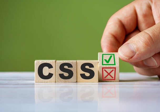 Το χέρι στροφή ξύλινο μπλοκ με κόκκινο απορρίπτουν Χ και πράσινο επιβεβαιώνουν τσιμπούρι ως αλλαγή έννοια της γλώσσας προγραμματισμού CSS. Εννοιολογικό σύμβολο CSS λέξης. - Φωτογραφία, εικόνα