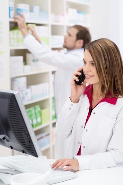 Pretty young pharmacist chatting on the phone - Photo, Image