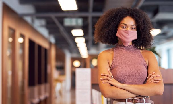 Portret van modieuze Afrikaanse zakenvrouw met gezichtsmasker op kantoor. - Foto, afbeelding