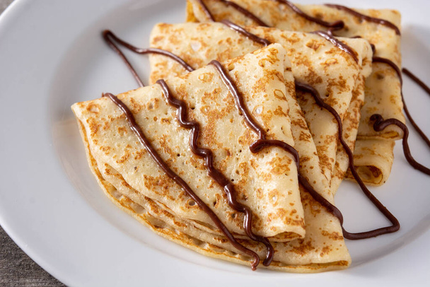 Sweet crepes with chocolate on wooden table - Фото, изображение