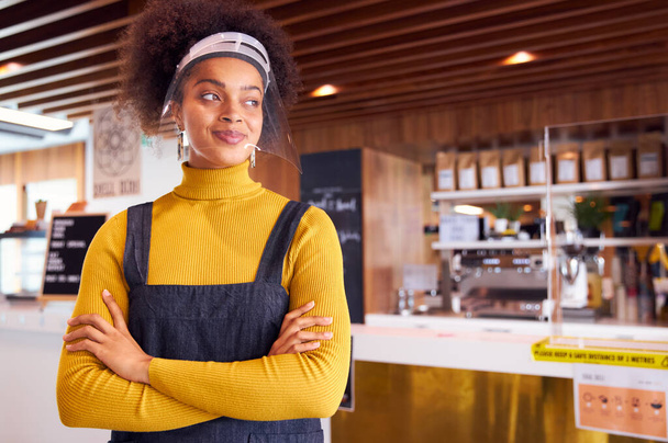 Female African coffee shop owner wearing face mask standing in front of counter - Photo, Image