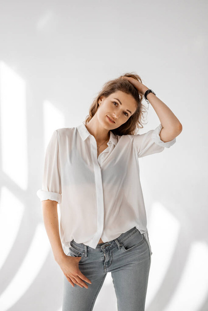 Young woman in white shirt on white background. Attractive girl in white clothes on a white background. - Foto, afbeelding