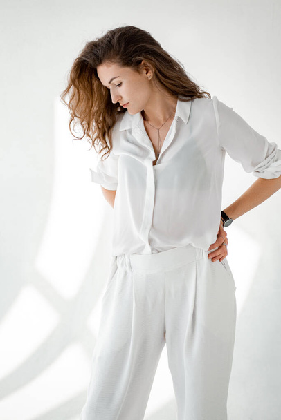 Mujer joven con camisa blanca sobre fondo blanco. Muchacha atractiva en ropa blanca sobre un fondo blanco. - Foto, imagen