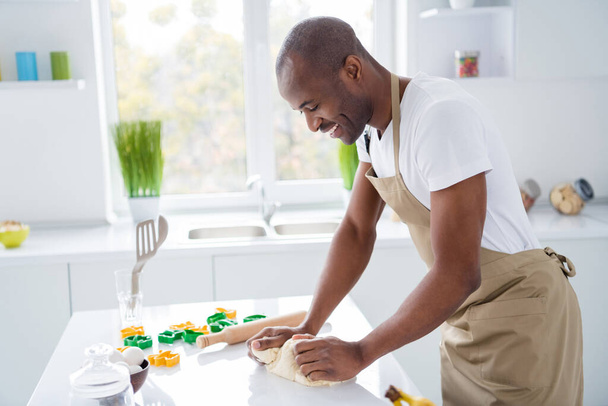 Profile side view portrait of nice cheerful guy confectioner making fresh bread pie pide doughing flour learning spending time vacation weekend quarantine in modern light white interior house kitchen - Fotó, kép