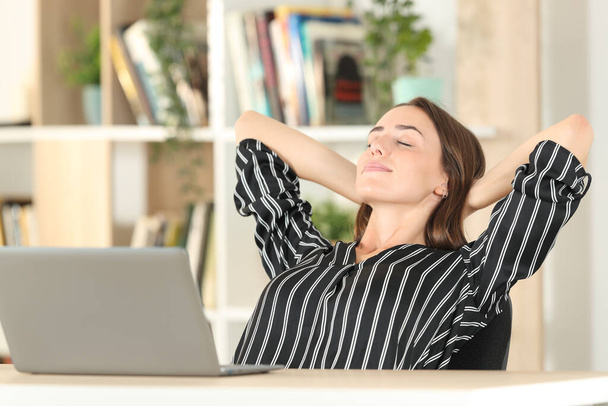 Satisfied woman relaxing sitting on a chair in a desktop at home - Foto, imagen