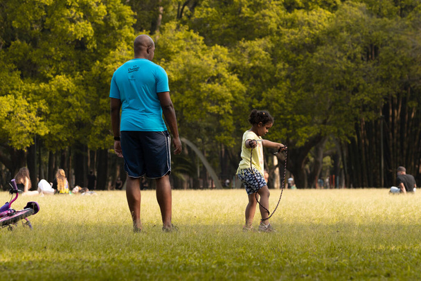 Чорний бразилець і його дочка стрибають мотузкою в парку - Сан-Паулу, Бразилія - 09 / 09 / 2020 - Фото, зображення