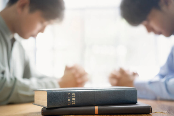 Dos personas cristianas están orando juntas sobre la sagrada Biblia. - Foto, imagen