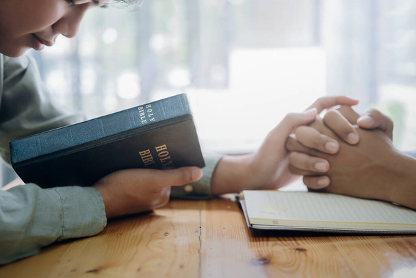 Dos personas cristianas están orando juntas sobre la sagrada Biblia. - Foto, imagen
