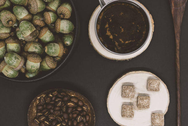 Tölgyfa makkok kávé háttér látható tölgyfa makkok, kávébab, barna kockacukor és fekete kávé bögre. Vintage hangszűrő szín stílus - Fotó, kép