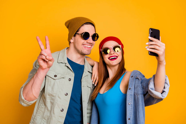 Close-up portrait of his he her she nice attractive glad cheerful cheery couple friends friendship taking selfie showing v-sign isolated over bright vivid shine vibrant yellow color background - 写真・画像