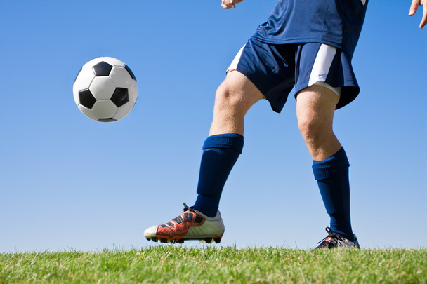 Athlete kicking a soccer ball on field - Zdjęcie, obraz