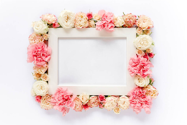 White frame decorated with pink roses flowers and leaves of eucalyptus. Flat lay, top view. Floral background. Floral frame. Frame of flowers. - Photo, image