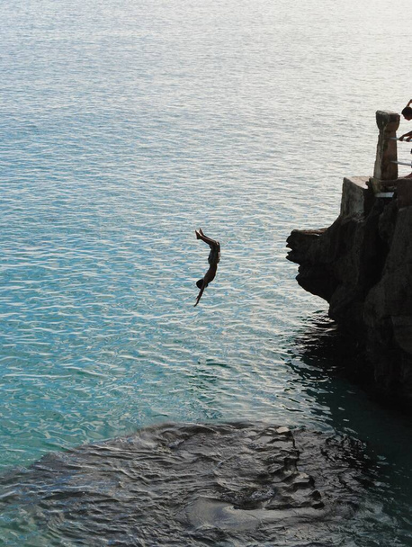 A boy somersaults off the edge of the Taga Beach cliff on Tinian, Northern Mariana Islands in February 2015. Taga Beach is the most popular destination in the island. - Foto, Bild