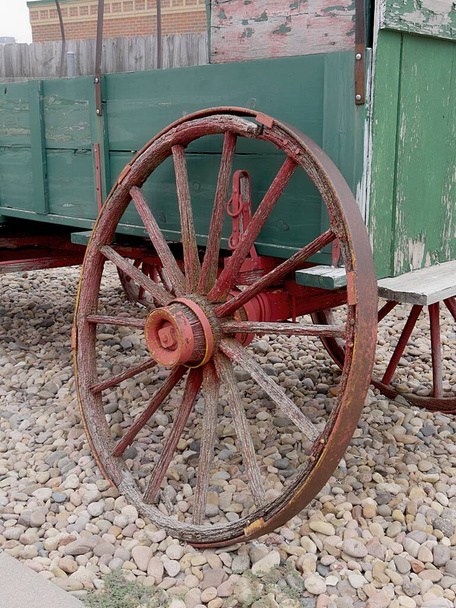 Carro de carro de madera viejo con ruedas rotas exhibidas en un suelo cubierto de roca  - Foto, imagen