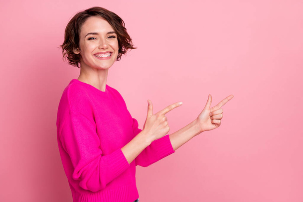 Photo of overjoyed excited lady toothy smiling directing fingers side empty space showing novelty sale discount banner wear casual bright sweater isolated pink pastel color background - Foto, immagini