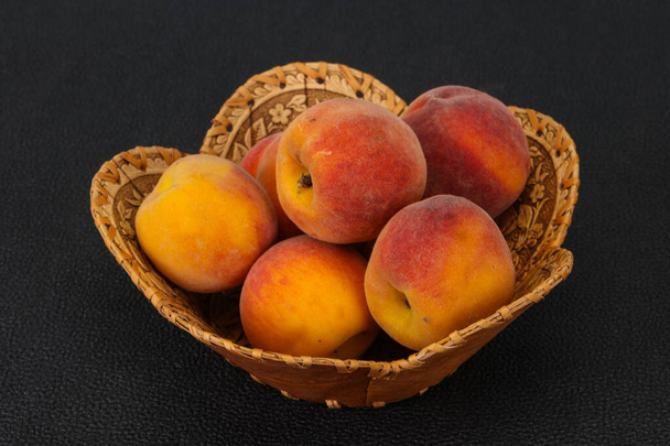 Спелые персиковые кучи в деревянной корзине - Фото, изображение
