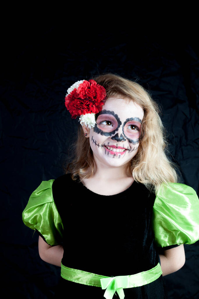A Caucasian girl dressed as a witch on Halloween and painted typically Mexican on the Day of the Dead - 写真・画像