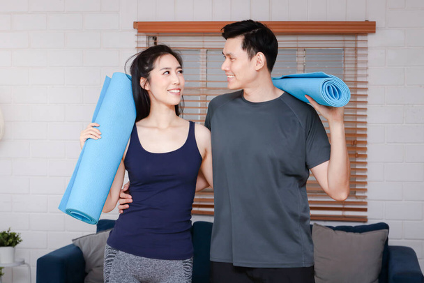 Les couples asiatiques font de l'exercice ensemble à la maison dans le salon. Maintenir une bonne santé et une bonne distance sociale pendant la COVID 19 - Photo, image
