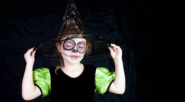 Uma menina caucasiana vestida de bruxa no Halloween e pintada tipicamente mexicana no Dia dos Mortos - Foto, Imagem