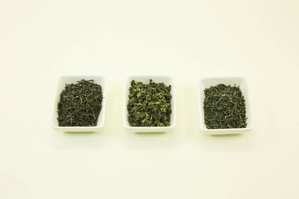 Kínai zöld tea különböző tartományokból. Zöld tea Pekingből, Wuhan-ból és Nanjing-ból. Fehér tálban, fehér alapon elkülönítve. - Fotó, kép