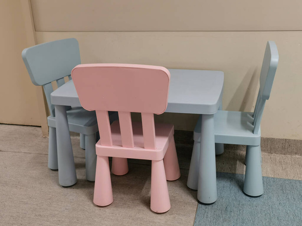 Ένα τραπέζι και τρεις άδειες πολύχρωμες παιδικές καρέκλες. - Φωτογραφία, εικόνα