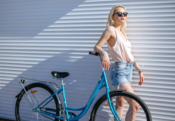 Woman with blond hair near bicycle isolated on white background. - Фото, зображення