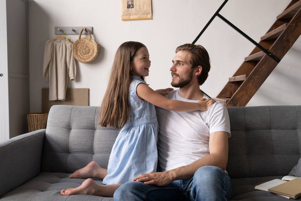 happy father and daughter hugging and sitting on sofa. - Foto, imagen