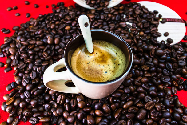 Taza de café con granos de café tostados sobre fondo rojo, concepto de café, foto de café de cerca - Foto, imagen