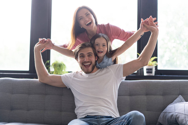 Happy cheerful parents having fun with cute children daughters playing on sofa - Foto, Imagem