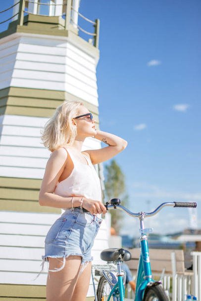 Woman leaning on the bicycle while standing near observation deck on the beach - Photo, Image