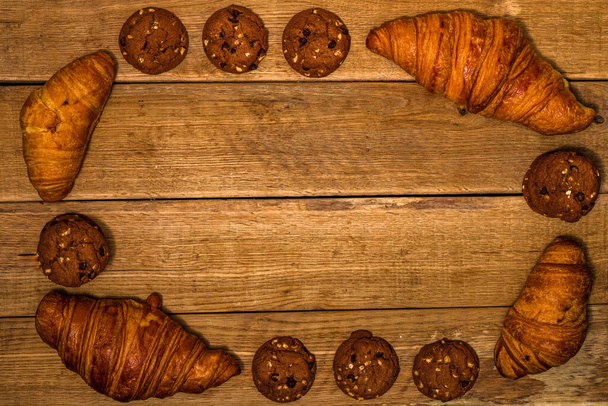 Свіжий круасан, листкове тісто та печиво на дерев'яному столі. Концепція їжі та сніданку. Десерти та свіжа випічка. Вид зверху і простір для копіювання
 - Фото, зображення