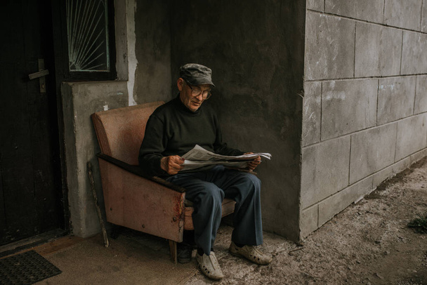 Un vecchio con gli occhiali con i capelli grigi sta leggendo un giornale - Foto, immagini
